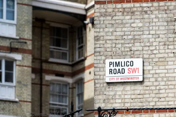 London neighborhood district of Pimlico, sign for SW1, city of Westminster, wire fence, old vintage historic brick traditional style flats