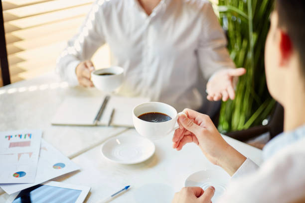 istock Crop businesspeople with coffee having discussion 1052347156