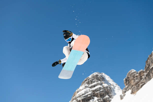 Shot of Young Snowboarder Practicing Big Air Young male snowboarder practicing free style snowboarding slopestyle stock pictures, royalty-free photos & images