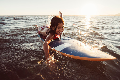 Little girl on surfboard in ocean.