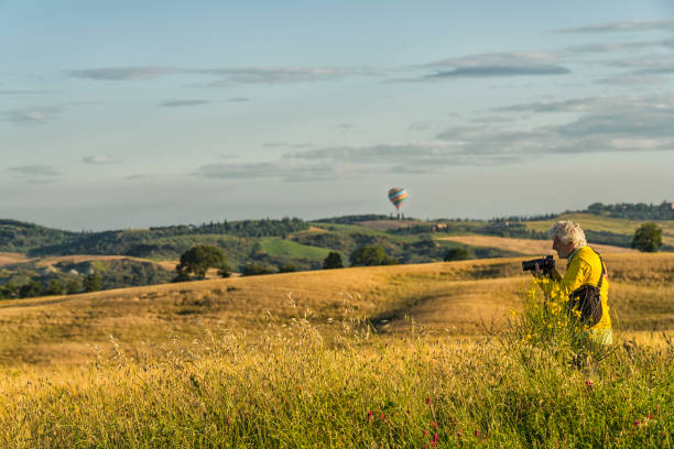 Senior men photographing wheat field on sunny day. Colorful balloon in background.