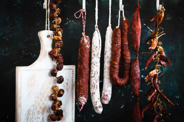 Chorizo salchichon fermented sausages salami hanging with dry pepper at market. Spanish hard sausages
