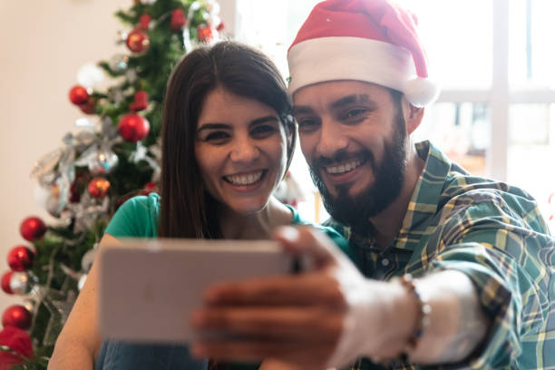 istock Cheerful young couple taking a selfie and man wearing santas hat 1052371642