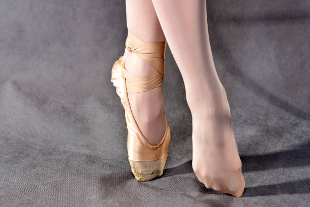 istock Ballerina legs in pointe shoes on grey background. 1052377506