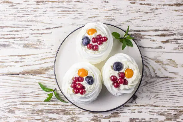 Photo of Delicious mini Pavlova meringue cake decorated with fresh red currant and blueberry