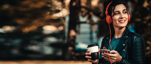 woman holding cup of coffee and listening music