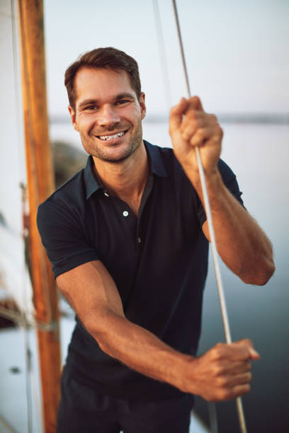 istock Smiling young man standing by ropes on his yacht 1052423788
