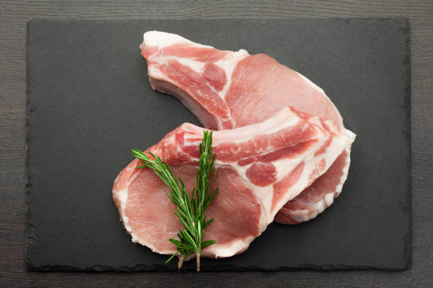istock fresh raw meat with rosemary on black slate, on dark background, pork, beef, chop on a bone 1052436798