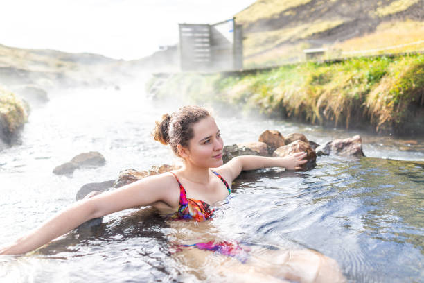 jovem mulher feliz natação banho em hveragerdi hot springs na trilha em reykjadalur, durante o outono de verão dia de manhã no sul da islândia, círculo dourado, pedras e vapor do rio - river swimming women water - fotografias e filmes do acervo