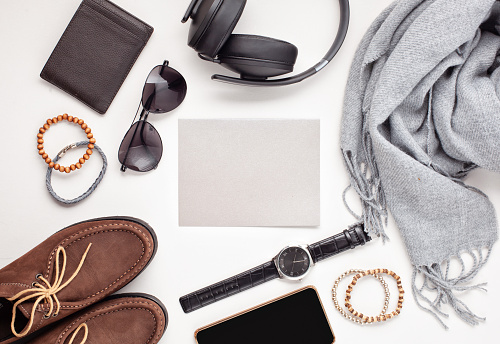 Flat lay of men's accessories with shoes, watch, phone, earphones, sunglasses, scarf over the orange background. Sales, Shopping, gift ideas. Top view