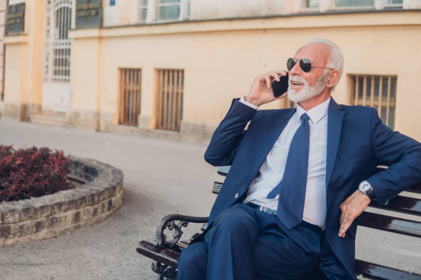 istock Man sitting on park bench and talking on phone 1052490070