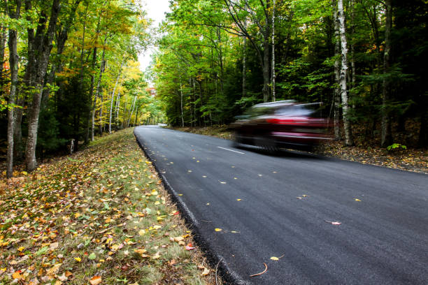 istock Car driving thru autumn road 1052509184