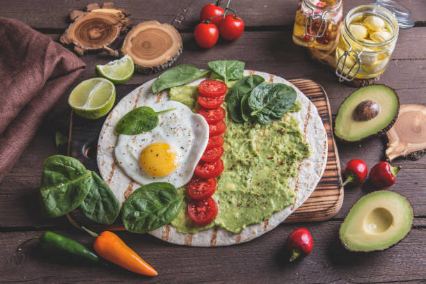 istock tortilla with guacamole avocado, fried egg and tomato, spinach leaves. vegetarian dish 1052543692