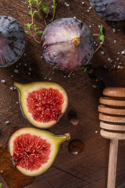 istock Fresh figs. Whole figs and sliced in half figs on wooden cutting board. 1052543822