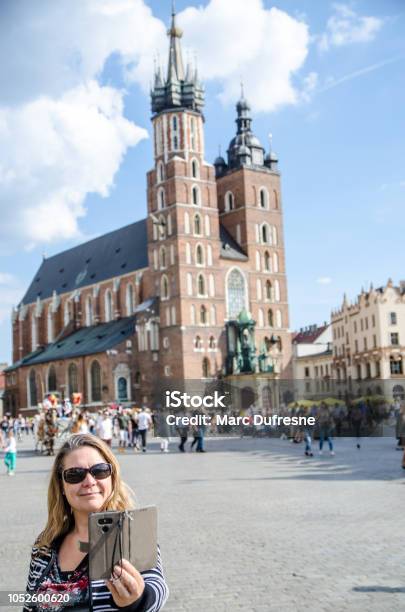 Woman Taking A Selfie While On Market Square With St Marys Cathedral In Background In Krakow Poland During Summer Day Stock Photo - Download Image Now