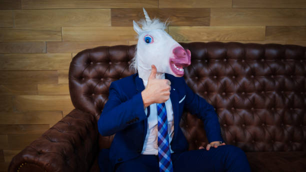 divertida unicornio en elegante traje se sienta en el sofá como un jefe - unicornio cabeza fotografías e imágenes de stock