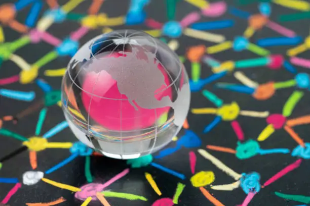 Globalization, US trade or world commerce, import, export or connectivity concept, small decoration globe with colorful pastel link and connect chalk line between multiple dots or tiers on blackboard.