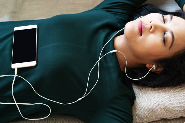 over head view of beautiful young woman laying down on sofa using smartphone to listen the music - female stripper imagens e fotografias de stock