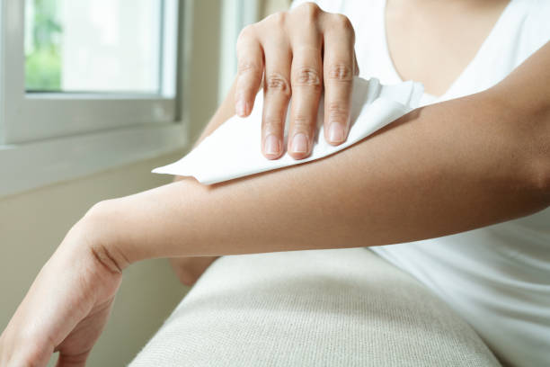 donna che pulisce il braccio con carta bianca di tessuto molle - panno per il viso foto e immagini stock