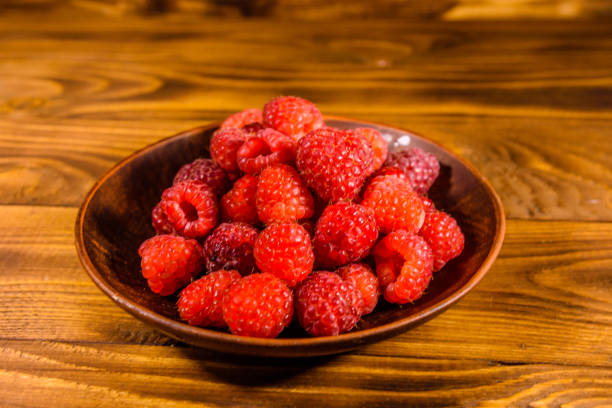 istock Ceramic plate with ripe raspberries on wooden table 1052890058