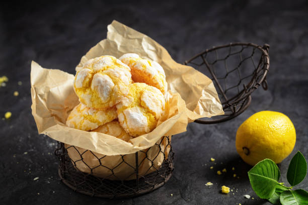 Homemade lemon crinkle cookies with powdered sugar icing on backing paper in small metal backed , on dark background stock photo