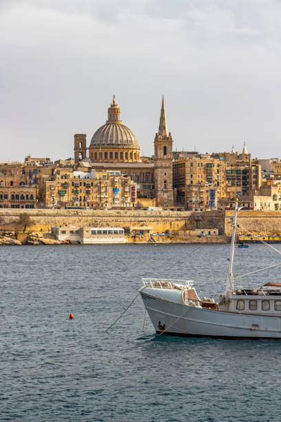 Valletta skyline with a boat in the foreground, at Valletta, Malta Valletta skyline as seen from Sliema, with a part of a boat in the foreground, at Valletta, Malta st paul cathedral la valletta malta island stock pictures, royalty-free photos & images
