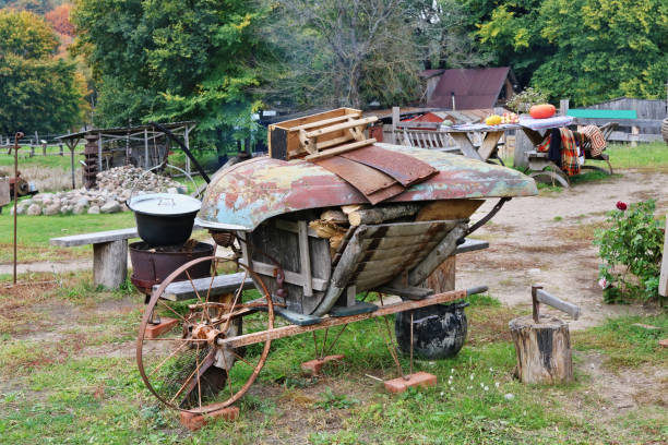 самодельный контейнер для дров изготовлен из старой деревянной тележки с железным колесом. - barn pan old red стоковые фото и изображения