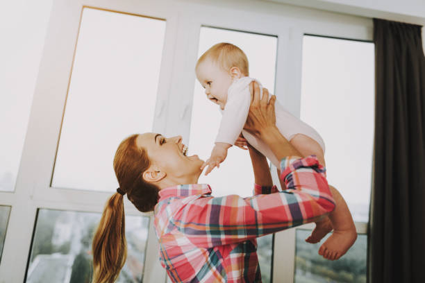 istock Happy Young Mother Throws Up Cute Child Indoors 1052914636