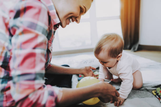istock Smiling Mother Playing with Cute Baby on Carpet 1052914656