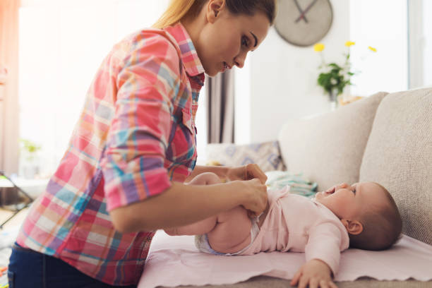 istock Careful Mother Swaddle Little Baby on Light Couch 1052914692