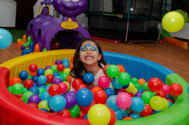 Little girl throwing herself in a pool full of colored balls stock photo