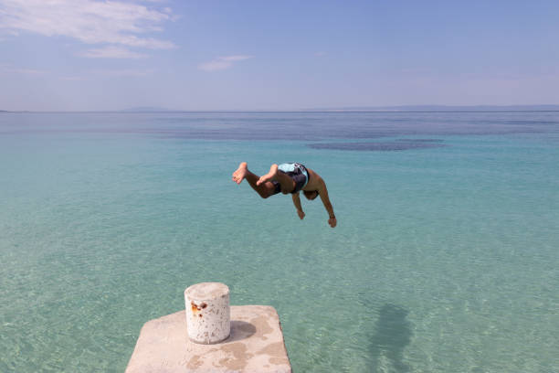istock Young man jumping into the sea from the pier 1052919870