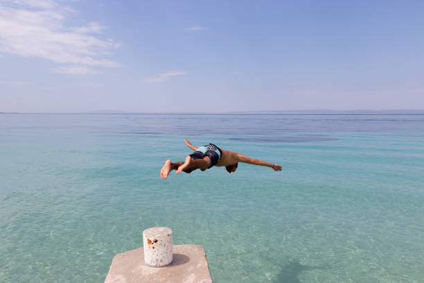 istock Young man jumping into the sea from the pier 1052919910