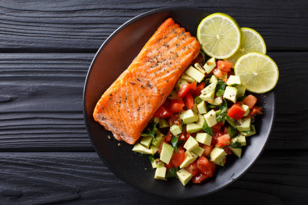 istock Fried salmon steak with avocado tomato salsa closeup. Horizontal top view 1052920040