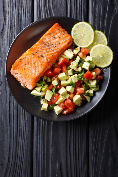 istock Fried salmon steak with avocado tomato salsa closeup. Vertical top view 1052920084