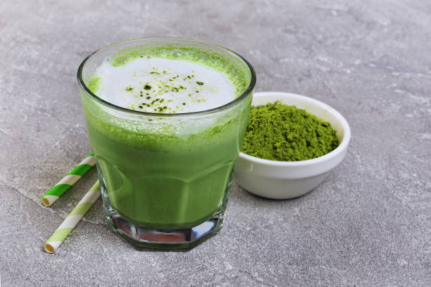 latte al tè matcha verde biologico in vetro e polvere in ciotola bianca - hot drink alcohol green glass foto e immagini stock