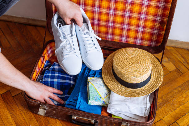 istock hands put sneakers to valise. packing for trip. travel concept 1052936134