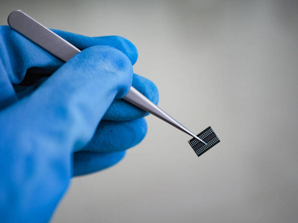 istock hand holding tweezers with IC on white background 1052937790