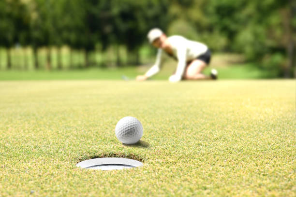 istock Woman golfer cheering after a golf ball on a golf green 1052938086