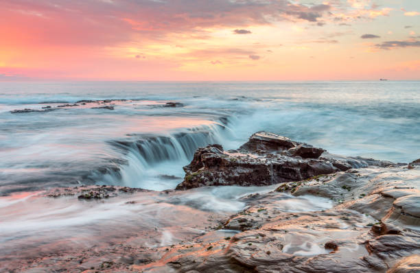 istock Sunrise with coastal waves washing over rocks 1052964382