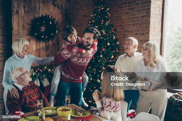 Noel Morning Large Gathering Couple Meeting Fairy Decoration December Tradition Greyhaired Grandparents Grandchildren Relatives Brother Son At House Feast Lunch Table Dad Piggybacking Girl Stock Photo - Download Image Now