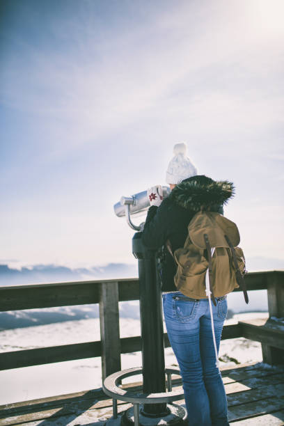 istock Tourist looking through binoculars in winter in snowy weather 1052969872