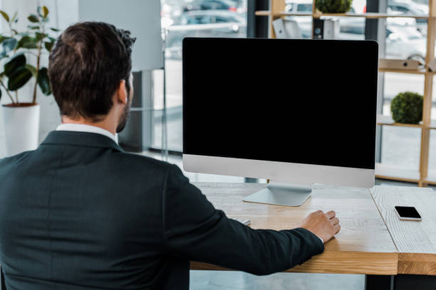 istock back view of businessman at workplace with computer screen with blank screen in office 1052975900