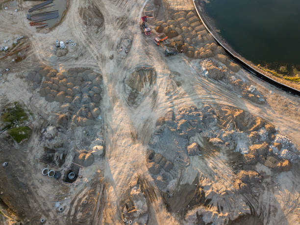istock Aerial view of three multi-colored dump tip trucks unloading in a designated place at a construction site, soil poured out from a quarry poured out of a quarry, around a large number of sand mounds 1052994884