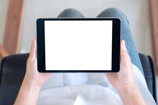 istock Top view mockup image of a woman holding black tablet pc with blank white screen while sitting on a chair 1052997254