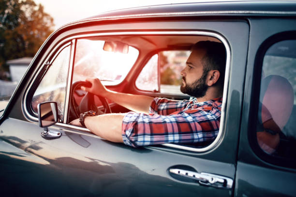 istock Man driving car at sunset 1053009186
