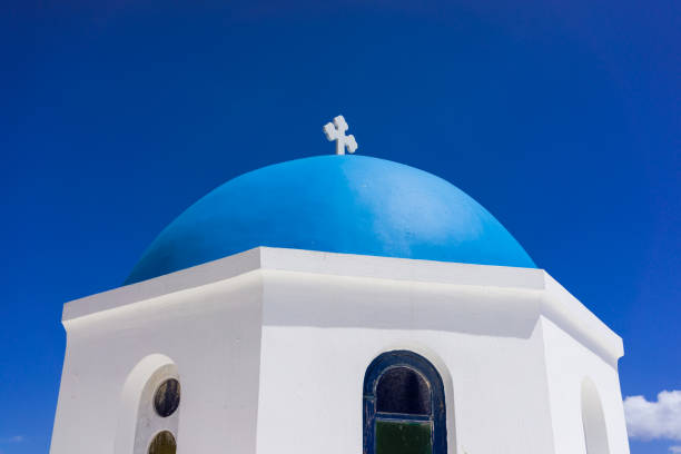 The blue dome of a church in the village of Oia Santorini Greece against a deep blue sky