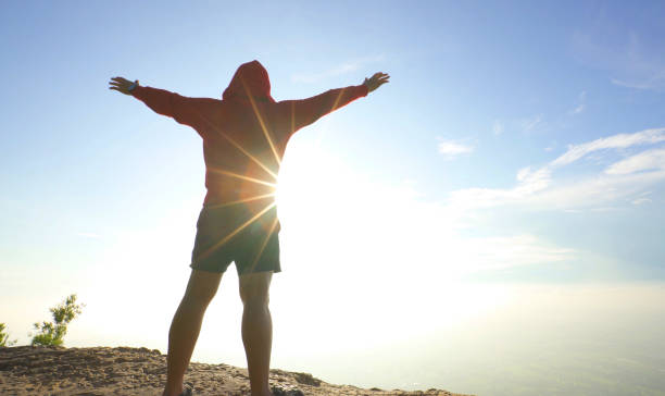 istock Happy man standing on mountain top bright sunny blue sky 1053011114