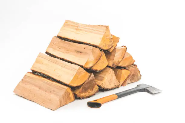 A stack of split firewood with axe on a white background