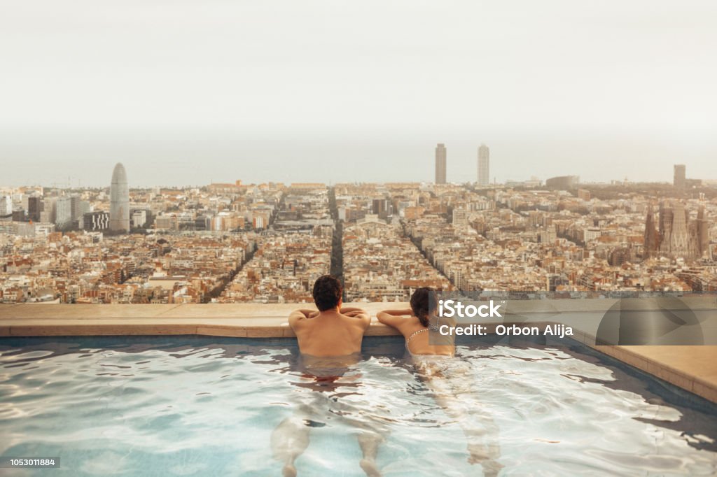 Couple relaxing on hotel rooftop looking at Barcelona city skyline. Photo composition. Barcelona - Spain Stock Photo